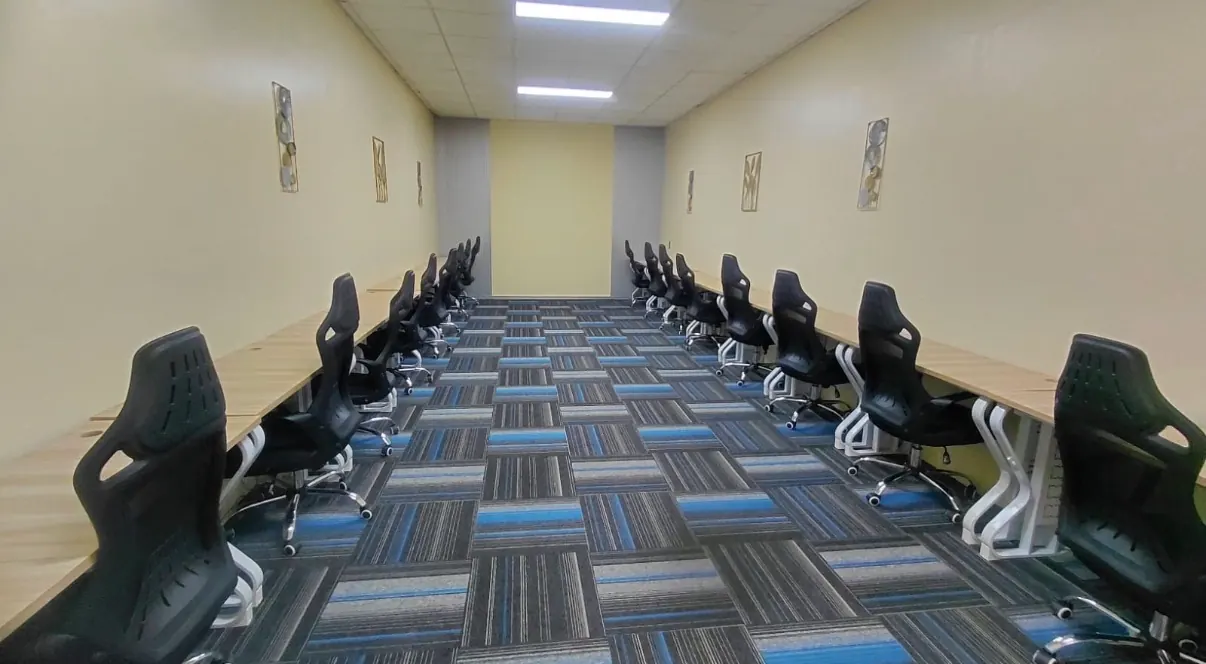 An empty training room with rows of desks and chairs.